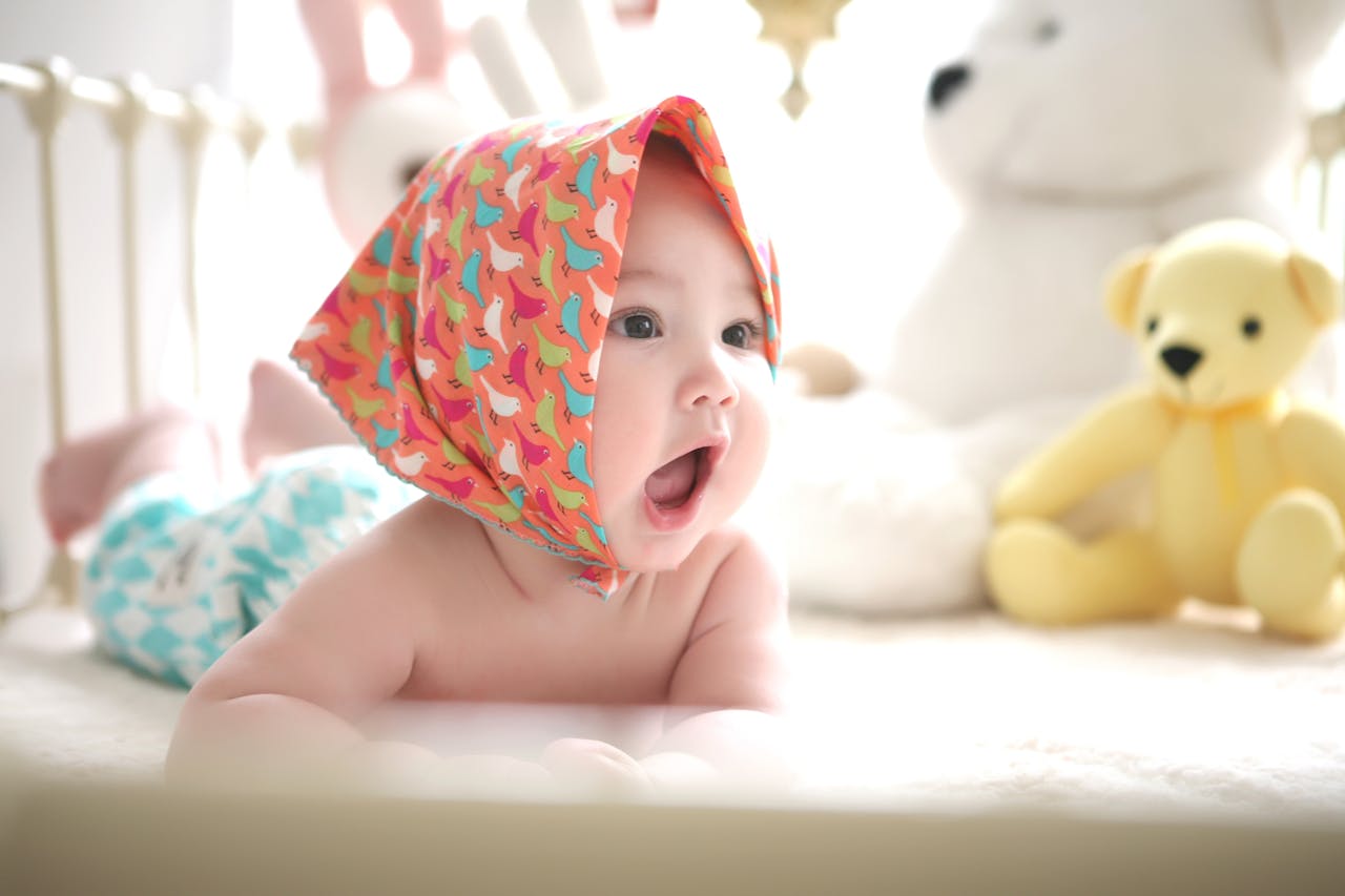 Services Charming baby with colorful scarf surrounded by cute plush toys, highlighting innocence indoors.