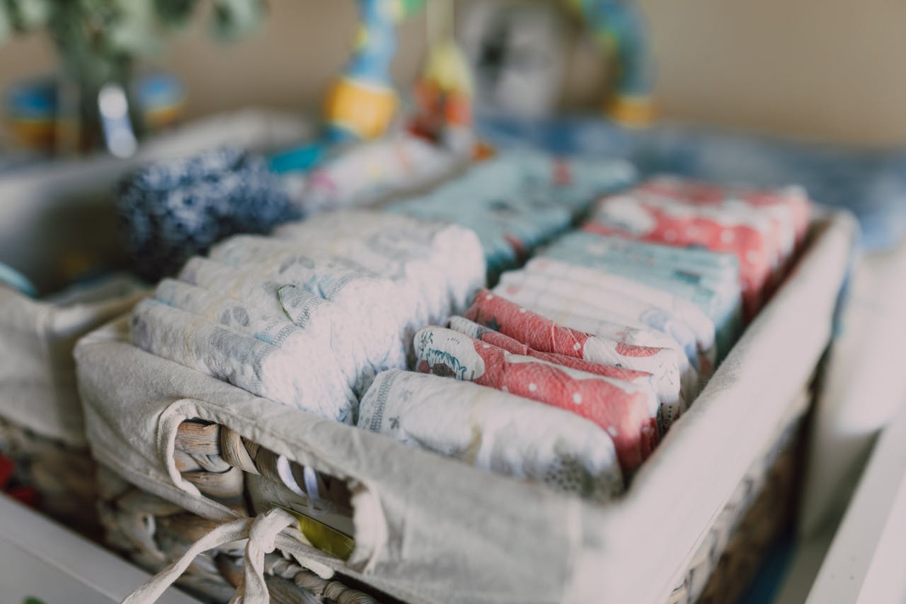 Services Close-up of neatly arranged colorful baby diapers in a woven basket, ideal for nursery organization.
