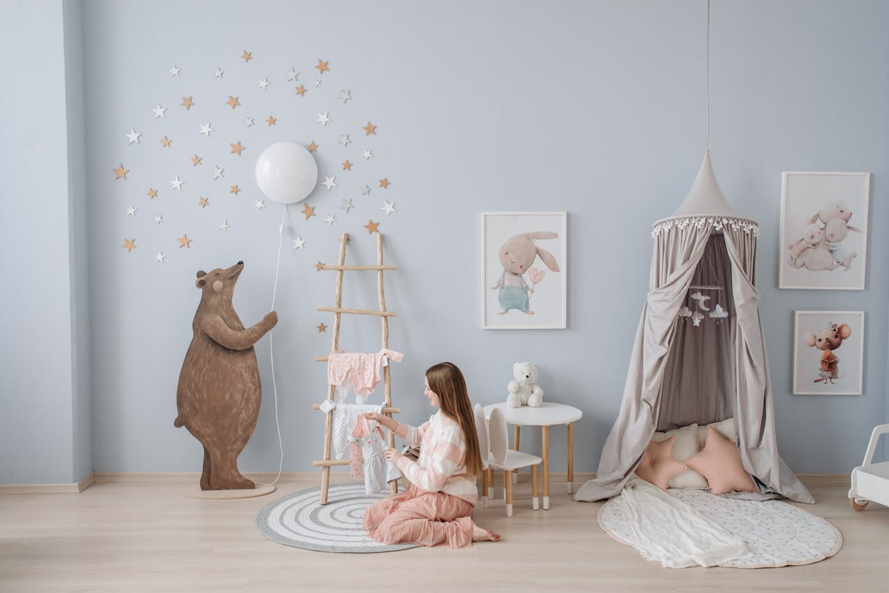 Home Woman arranging baby clothes in a beautifully decorated nursery with playful decor.